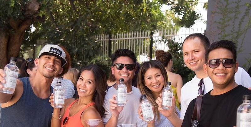 A group of guests holding bottled drinks at an outdoor brand event