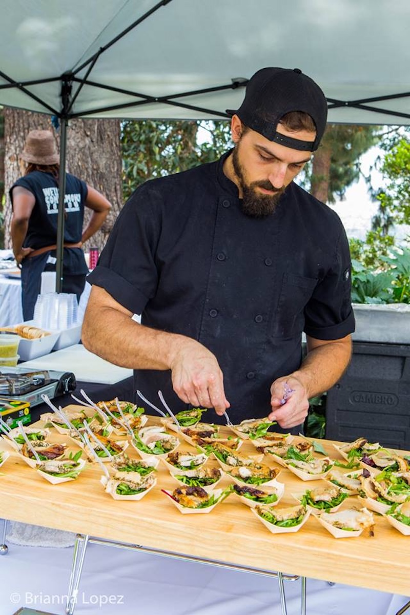 A chef preparing tasting plates at an outdoor food event