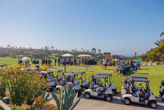 Golf carts and tournament guests overlooking a coastal golf course