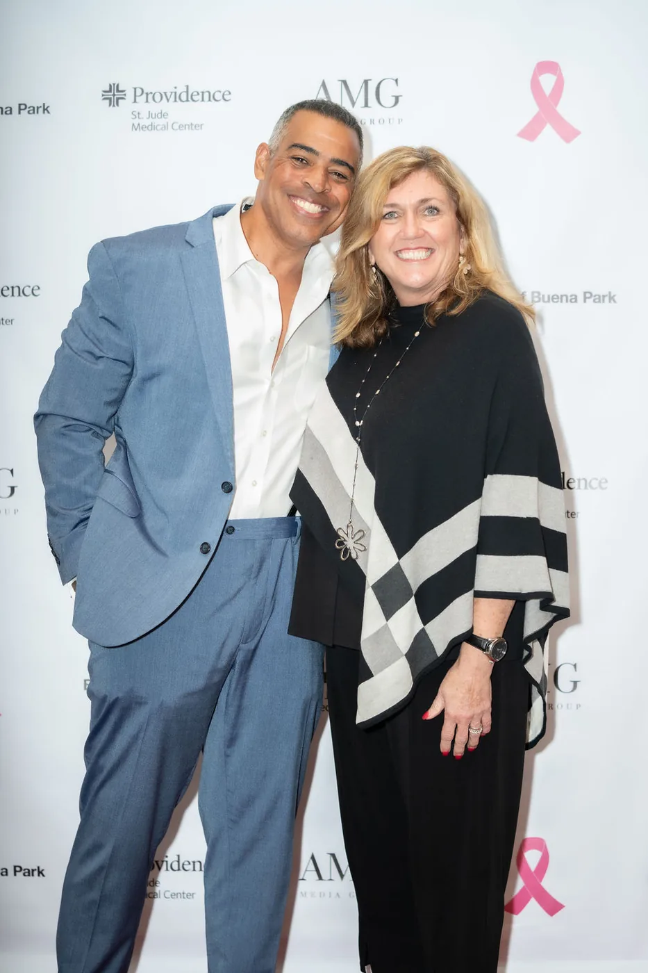 Two guests in front of the Providence and AMG pink ribbon event backdrop